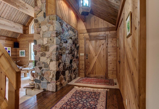 interior space featuring beam ceiling, dark wood-type flooring, wooden ceiling, high vaulted ceiling, and wooden walls