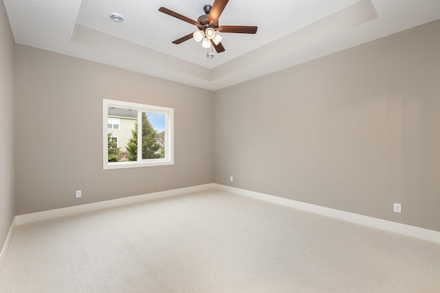 spare room featuring carpet flooring, a raised ceiling, and ceiling fan