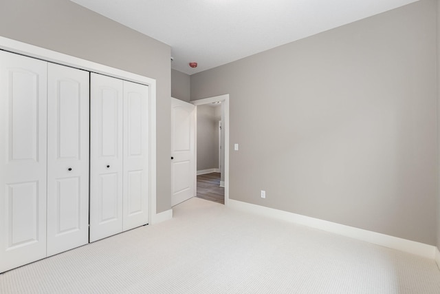 unfurnished bedroom with light colored carpet and a closet