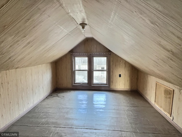 additional living space with wooden walls and vaulted ceiling