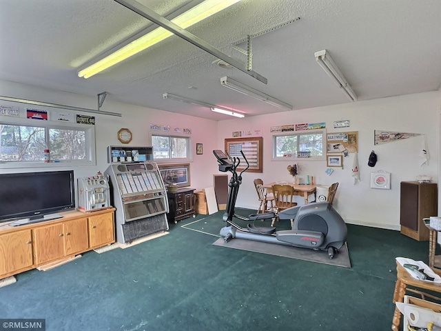 workout room featuring plenty of natural light, dark carpet, and a textured ceiling