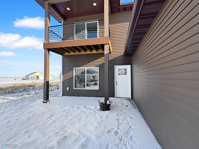 snow covered property entrance featuring a balcony