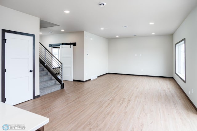 spare room featuring a barn door and light hardwood / wood-style flooring