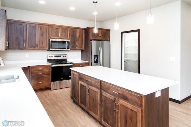 kitchen with a center island, sink, hanging light fixtures, light hardwood / wood-style flooring, and appliances with stainless steel finishes