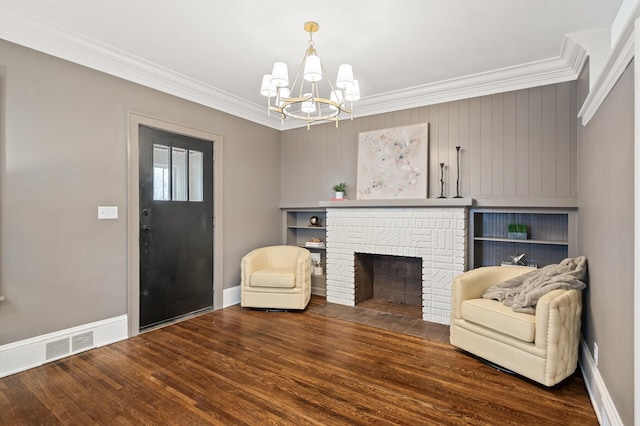 sitting room featuring an inviting chandelier, dark hardwood / wood-style flooring, ornamental molding, and a brick fireplace