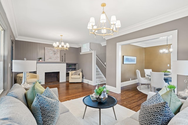 living room with crown molding, a fireplace, an inviting chandelier, and hardwood / wood-style flooring