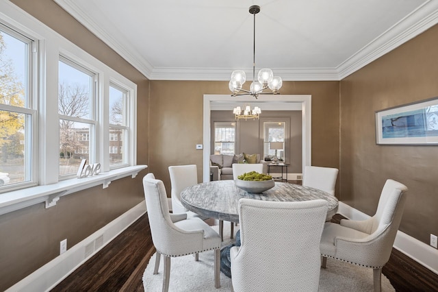 dining room with dark wood-type flooring, a healthy amount of sunlight, and a notable chandelier