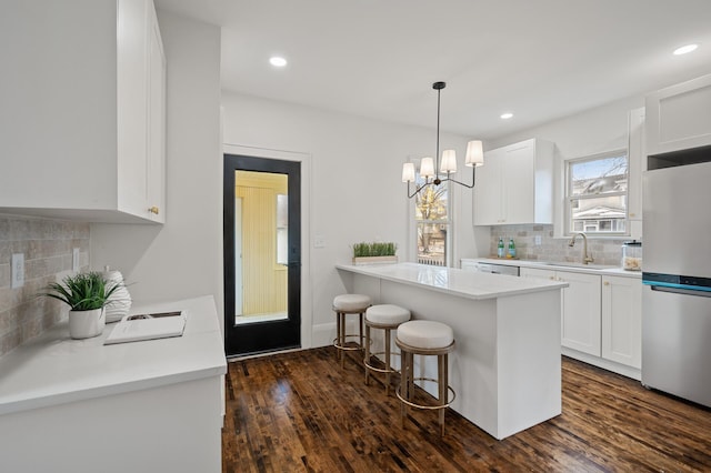 kitchen with a kitchen bar, white cabinetry, dark wood-type flooring, and white refrigerator