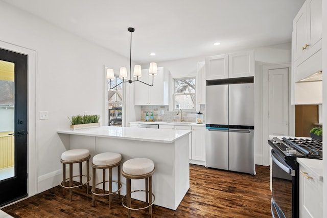 kitchen featuring kitchen peninsula, appliances with stainless steel finishes, dark hardwood / wood-style flooring, and white cabinetry