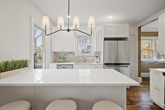 kitchen with sink, light stone counters, dark hardwood / wood-style floors, a breakfast bar, and appliances with stainless steel finishes