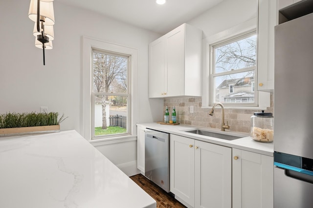 kitchen featuring white cabinets, appliances with stainless steel finishes, plenty of natural light, and hanging light fixtures