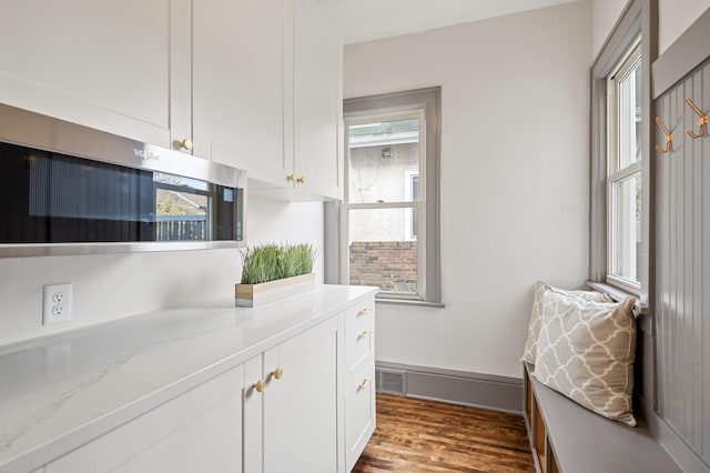 interior space with wood-type flooring, white cabinetry, and light stone counters