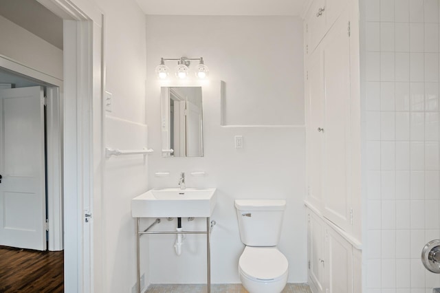 bathroom featuring wood-type flooring, toilet, and sink