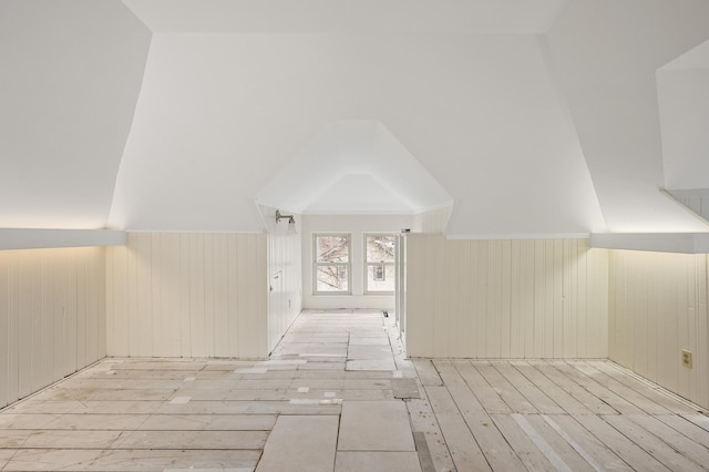 bonus room with wood walls, lofted ceiling, and light hardwood / wood-style flooring