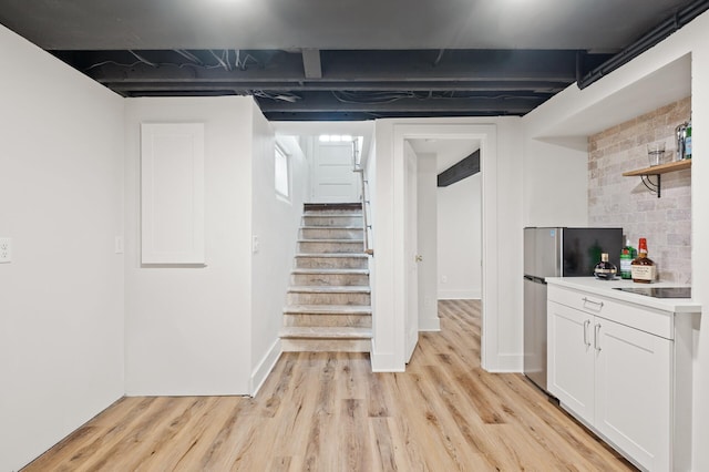 basement with stainless steel refrigerator and light wood-type flooring