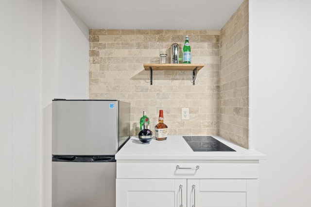 kitchen featuring black electric stovetop, white cabinetry, stainless steel refrigerator, and tasteful backsplash