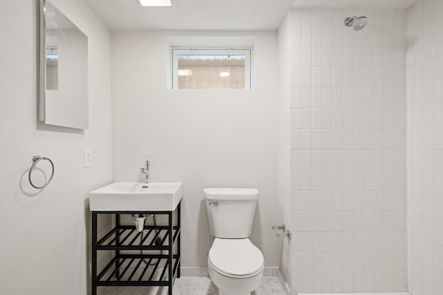 bathroom featuring tiled shower, sink, tile patterned flooring, and toilet