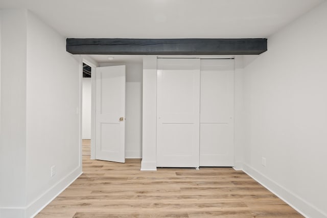 interior space featuring a closet, light hardwood / wood-style flooring, and beamed ceiling