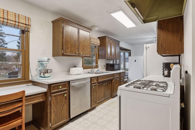 kitchen featuring stainless steel dishwasher, plenty of natural light, white range oven, and sink