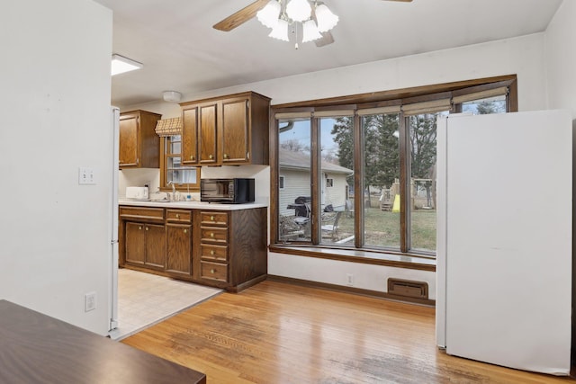 kitchen featuring ceiling fan, sink, white fridge, and light wood-type flooring