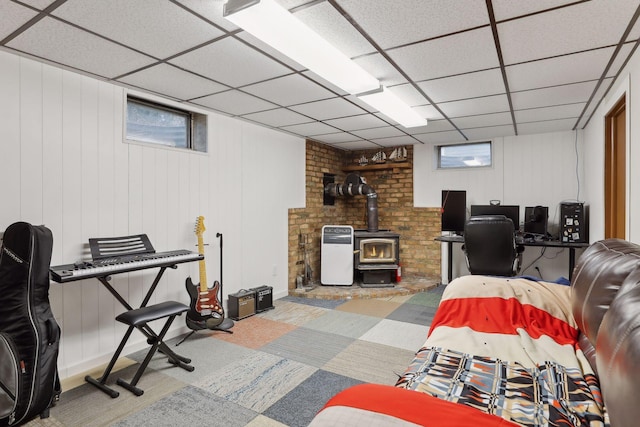 interior space featuring a paneled ceiling and a wood stove