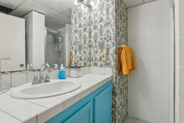 bathroom with a drop ceiling, vanity, and an enclosed shower