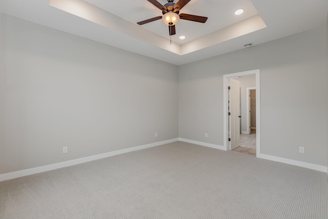 carpeted empty room featuring a raised ceiling and ceiling fan