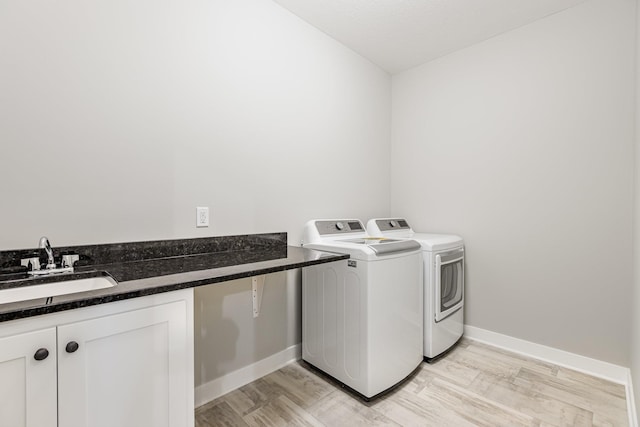 laundry area featuring washer and clothes dryer, light hardwood / wood-style flooring, and sink