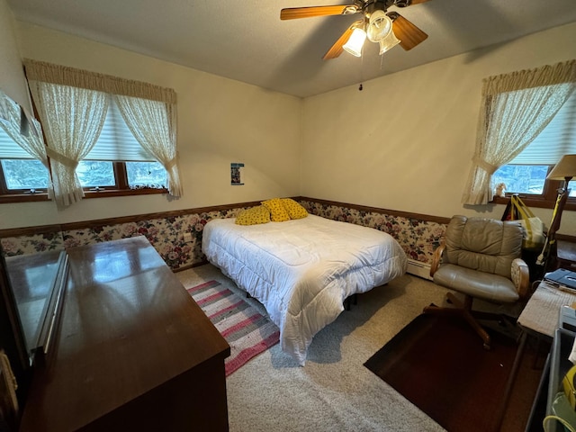 bedroom with carpet floors, ceiling fan, and a baseboard heating unit