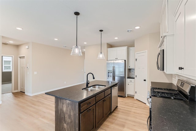 kitchen with a kitchen island with sink, sink, light hardwood / wood-style flooring, appliances with stainless steel finishes, and white cabinetry