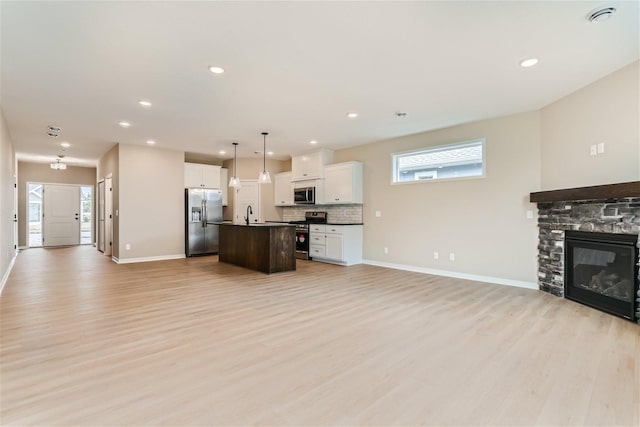 kitchen featuring decorative light fixtures, stainless steel appliances, a wealth of natural light, and an island with sink