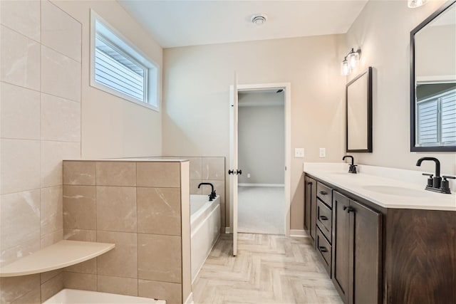 bathroom with vanity, parquet floors, and tiled tub