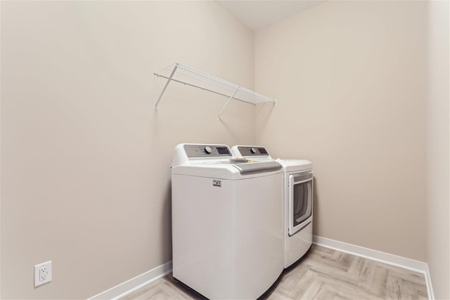 clothes washing area featuring light parquet flooring and washer and clothes dryer