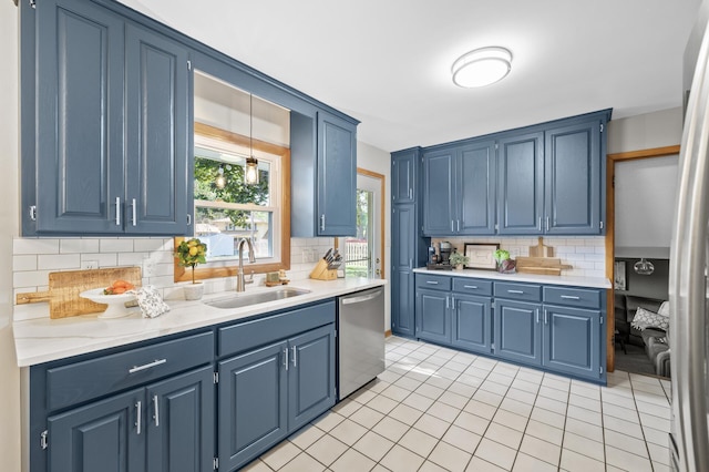 kitchen featuring pendant lighting, sink, stainless steel dishwasher, blue cabinetry, and tasteful backsplash