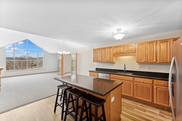 kitchen featuring a center island, sink, stainless steel appliances, an inviting chandelier, and a breakfast bar