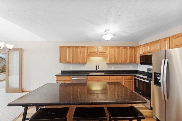 kitchen with a breakfast bar, sink, a kitchen island, and appliances with stainless steel finishes