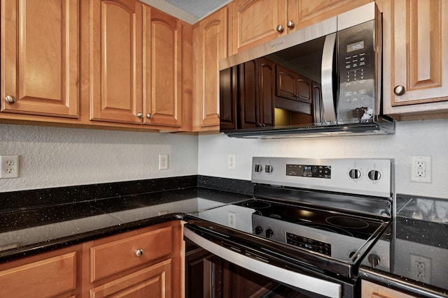 kitchen with dark stone countertops and appliances with stainless steel finishes