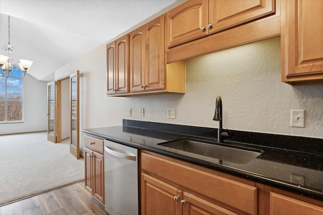 kitchen with dishwasher, dark stone counters, sink, a notable chandelier, and light hardwood / wood-style floors