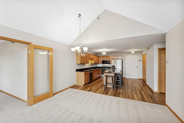 kitchen featuring sink, hanging light fixtures, hardwood / wood-style flooring, appliances with stainless steel finishes, and a kitchen island