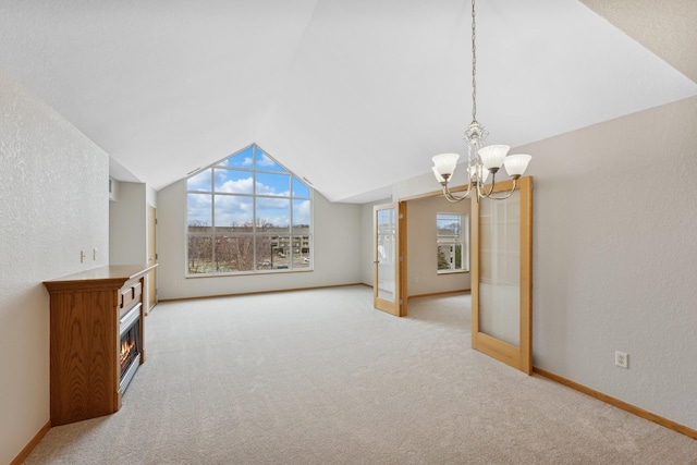 unfurnished living room featuring a notable chandelier, light carpet, and vaulted ceiling