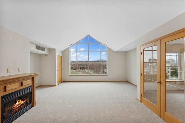 unfurnished living room with light colored carpet, lofted ceiling, and french doors