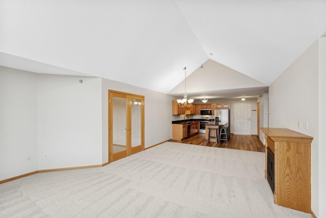 carpeted living room featuring french doors, sink, lofted ceiling, and an inviting chandelier