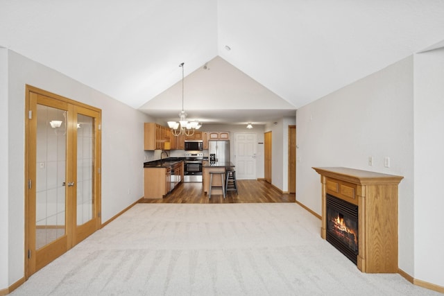 carpeted living room featuring sink, lofted ceiling, french doors, and an inviting chandelier