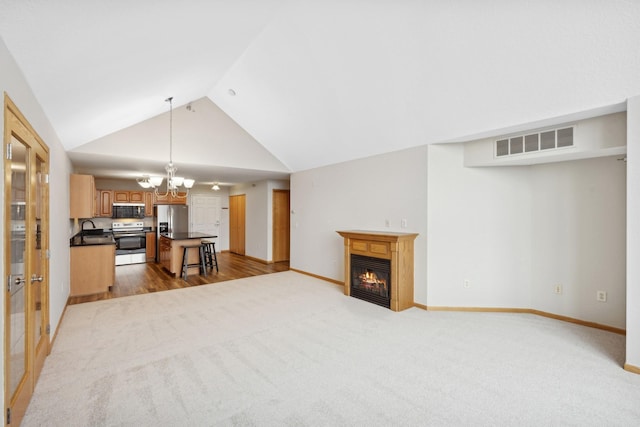 unfurnished living room with light carpet, sink, vaulted ceiling, and an inviting chandelier