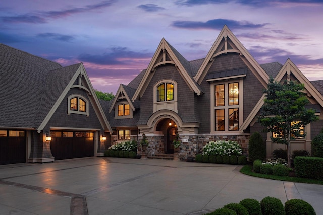 view of front of property featuring driveway, a garage, and roof with shingles