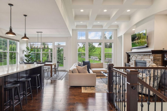 living room with coffered ceiling, dark hardwood / wood-style flooring, beamed ceiling, a towering ceiling, and a fireplace