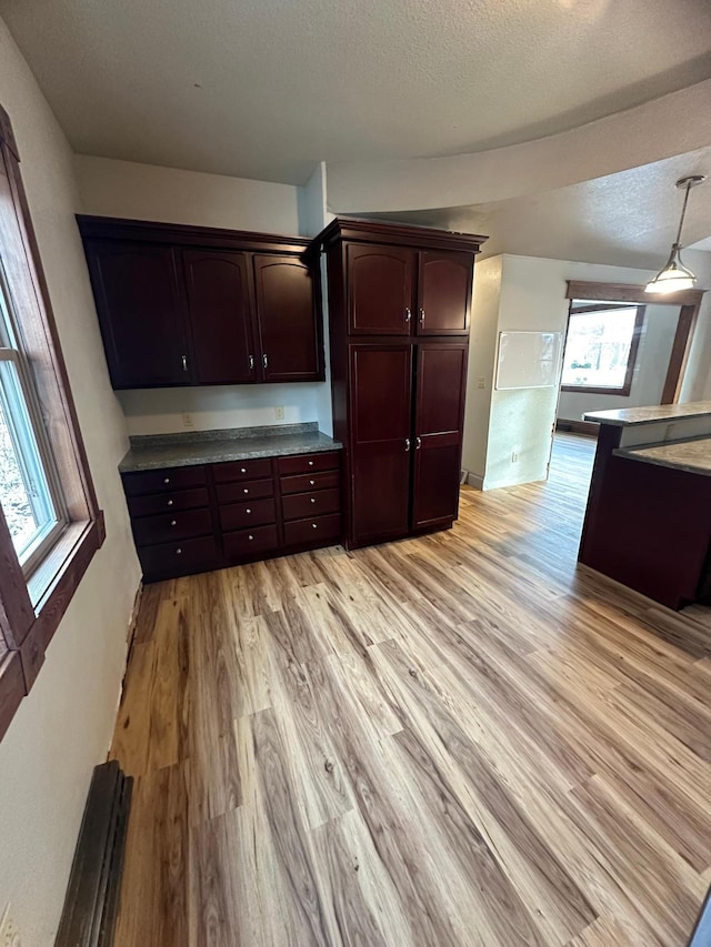 kitchen with decorative light fixtures, a textured ceiling, and light hardwood / wood-style floors