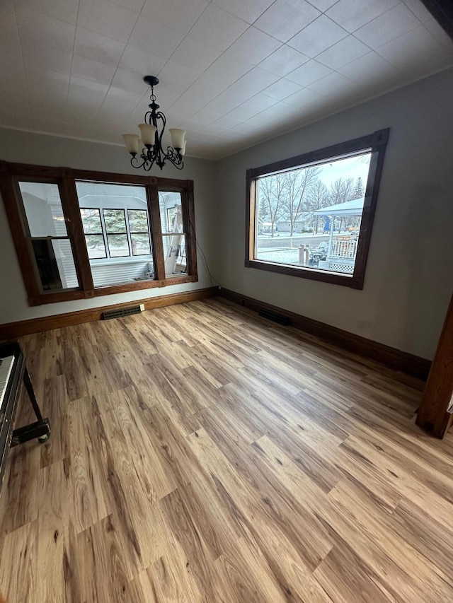 unfurnished dining area featuring light wood-type flooring and an inviting chandelier