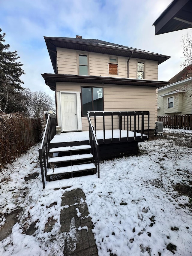 snow covered back of property with central air condition unit and a wooden deck