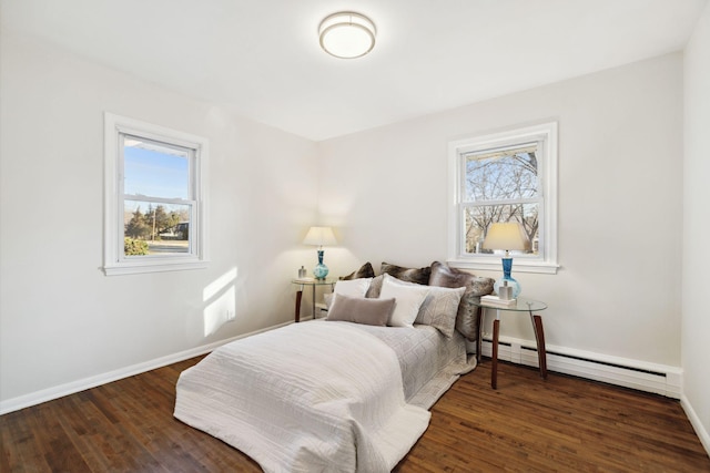 bedroom with a baseboard radiator, multiple windows, and dark wood-type flooring